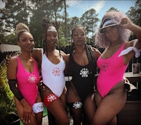 four women in pink and black swimsuits posing for a photo