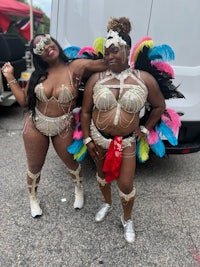 two women in colorful costumes standing next to a van