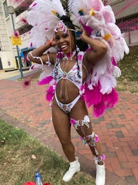 a woman in a pink and white costume standing on a sidewalk